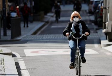 mulher andando de bicicleta com máscara