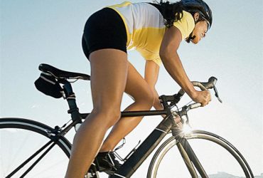 Mulher ciclista em sua bicicleta com roupas adequadas para a prático do ciclismo