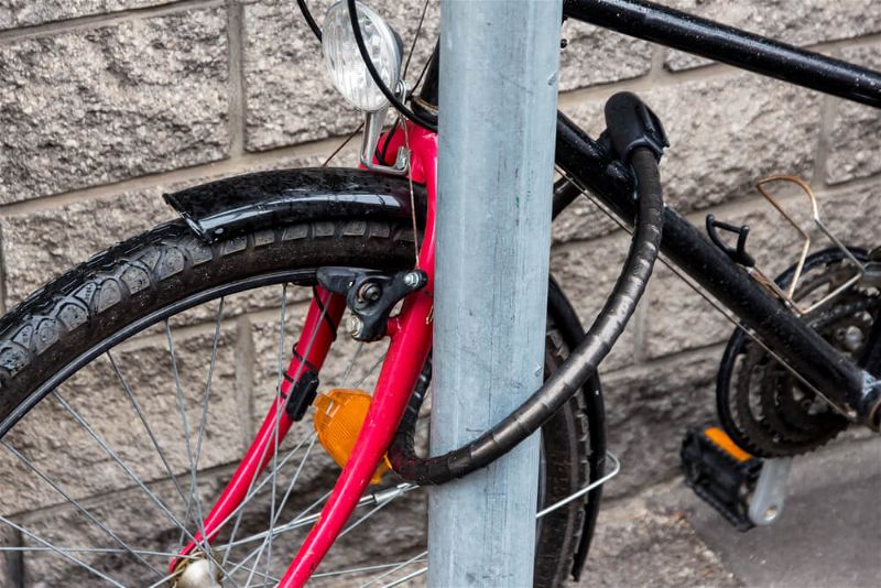 Bicicleta amarrada em post com cadeado