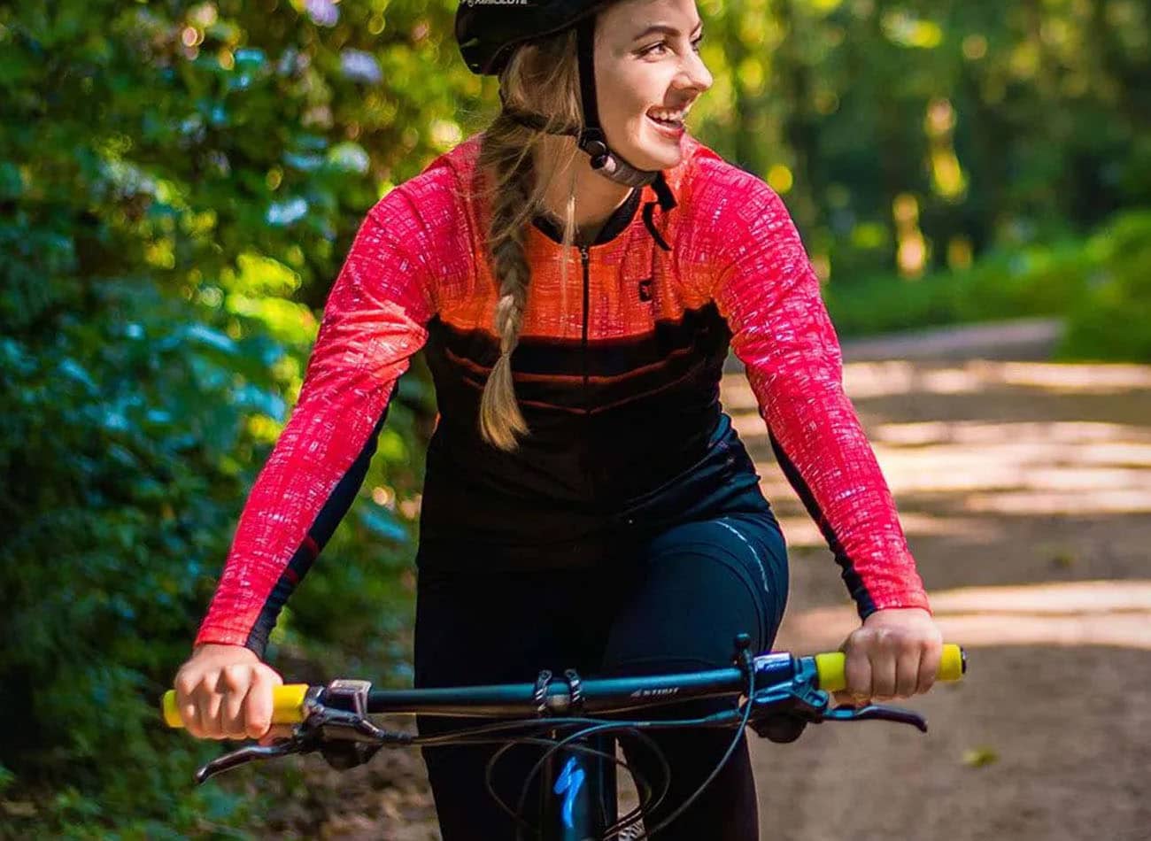 mulher pedalando sorrindo usando roupa de ciclismo rosa
